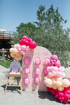 pink and white balloons are on display in front of a sign