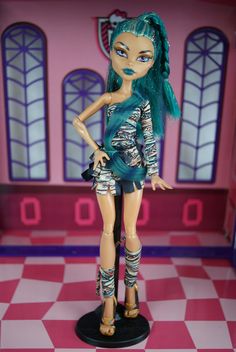 a doll with green hair standing in front of a pink and white checkered floor