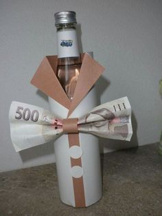 a bottle wrapped in brown paper and tied to a ribbon with money inside it, sitting on a counter