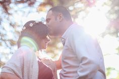 a man and woman standing next to each other in front of trees with the sun shining on them