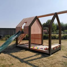 a small wooden structure with a slide in the middle and a house shaped like a building