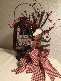 a christmas arrangement with red and white gingham bows, an old fashioned lantern and a wooden ornament