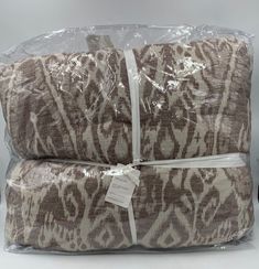 two brown and white pillows wrapped up in plastic wrap on top of eachother