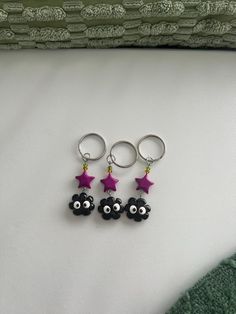 three little black sheep with pink stars hanging from them's earwires on a white surface