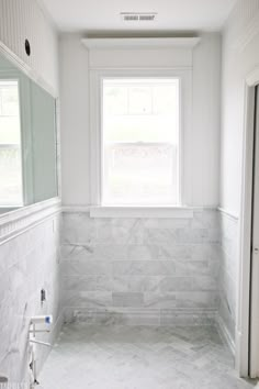 a bathroom with marble floors and white walls, along with a window in the corner