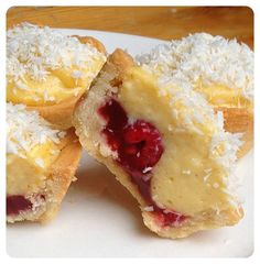 three pastries on a white plate with coconut and raspberry toppings are cut in half