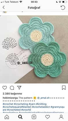 two crocheted flower appliques sitting on top of a piece of paper