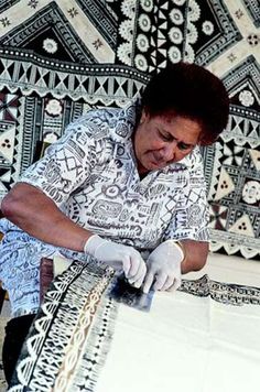 a man in white shirt and gloves working on an area rug with black and white designs