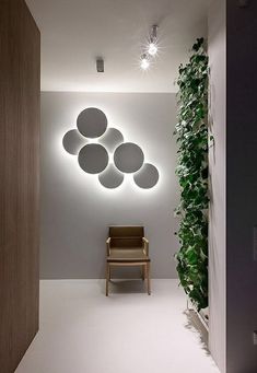 a chair sitting in front of a white wall with circular lights on it's side