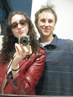 a man and woman taking a selfie in front of a mirror with a camera