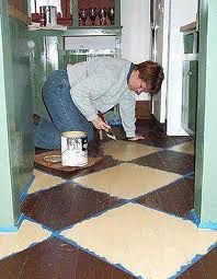 a man is painting the floor in his kitchen with brown and white tiles on it