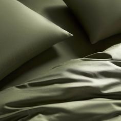 a bed with green sheets and pillows on it