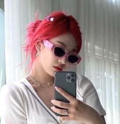 a woman with red hair and sunglasses is looking at her cell phone