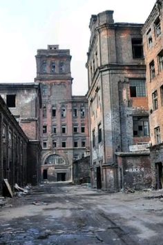 an old run down building with graffiti on the walls and floors, in front of other buildings