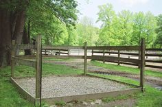 a wooden fenced in area with grass and dirt on the ground next to trees