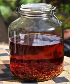 a glass jar filled with liquid sitting on top of a checkerboard tablecloth