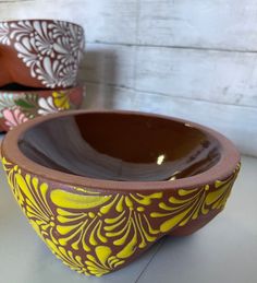 two bowls sitting on top of a table next to each other, one with yellow and brown designs