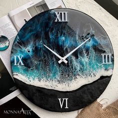 a clock that is sitting on top of a table next to an open book and magazine