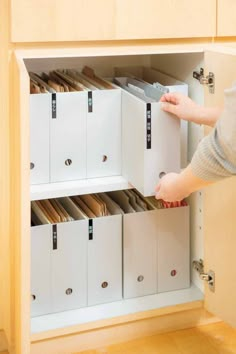 a person is opening the drawers in a cabinet with many file folders on it