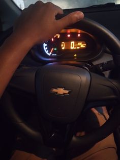 a person driving a car with their hand on the steering wheel and an illuminated dashboard