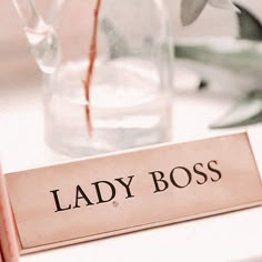 a lady boss sign sitting on top of a table next to a vase filled with flowers