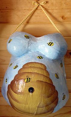 a ceramic sculpture of a bear with honeycombs on it's chest hanging from a rope