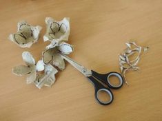 a pair of scissors sitting on top of a wooden table next to flowers and leaves