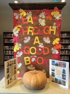 a pumpkin sitting on top of a table in front of a sign that says leaf through a good book