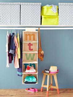 an organized closet with clothes hanging on the wall and shoes sitting on stools next to it