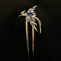 Pieces are attached using a special jewelry adhesive. Please read descriptions thoroughly for sizes and materials.  Rise from the ashes! This is a majestic u shaped gold metal hair fork featuring a gorgeous gold metal Phoenix bird. It's wings are out stretched, in flight, and it has a long curved tail. It has white glass gems on the head, wings, and tail, a large faceted blue gem on the body, and blue and white enamel on the wings. It is a really fun way to dress up any bun my hair style, and es Phoenix Blue, Head Wings, Phoenix Hair, Hair Accessories Bun, Phoenix Jewelry, Character Board, Rise From The Ashes, Phoenix Bird, Phoenix Rising