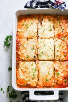 a casserole dish filled with lasagna and sauces, garnished with parsley