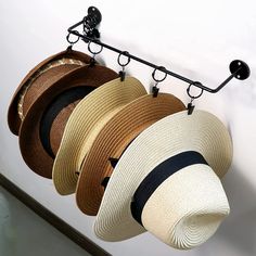 three hats are hanging from a hook on the wall