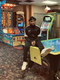 a man sitting on top of a table in front of a pinball game machine