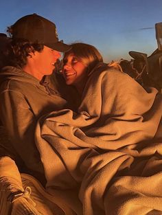 two people wrapped up in blankets sitting next to each other