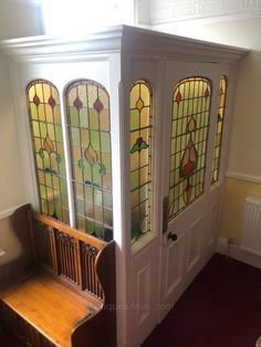 an entryway with stained glass windows and a bench in the corner, next to a radiator