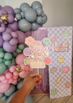 a person holding up a cake topper in front of some balloons and other decorations