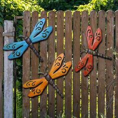 three metal dragon sculptures sitting on top of a wooden fence