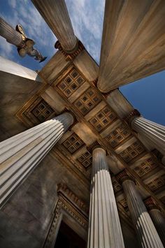 looking up at the ceiling and columns in an old building with blue sky behind it