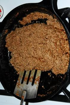 a frying pan filled with food sitting on top of a stove next to a spatula