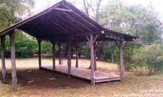 a wooden gazebo sitting in the middle of a forest