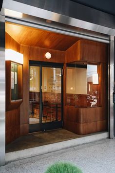 the entrance to an office building with glass doors and wood paneling on the outside