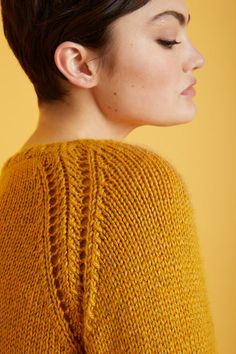 a woman with short hair wearing a yellow sweater