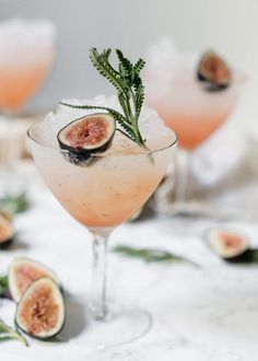 two glasses filled with watermelon cocktails and garnished with fresh herbs