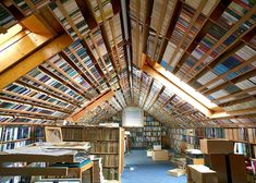 a room filled with lots of books on top of wooden shelves next to a ceiling