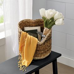 a basket filled with books and flowers sitting on top of a table next to a window