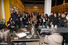 a large group of people standing around a table in a room with bookshelves