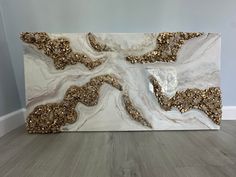 a large white and gold painting on top of a wooden floor