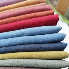 a stack of different colored jeans sitting on top of a table