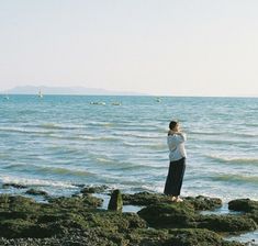 a man standing on top of a rocky beach next to the ocean