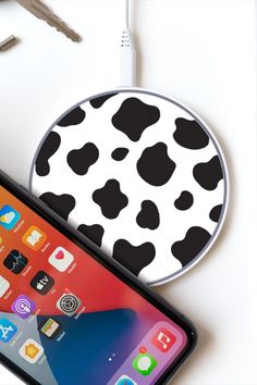 an iphone with a black and white cow pattern on it next to a charger